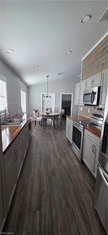 Kitchen featuring butcher block counters, stove, pendant lighting, dark wood finished floors, and recessed lighting