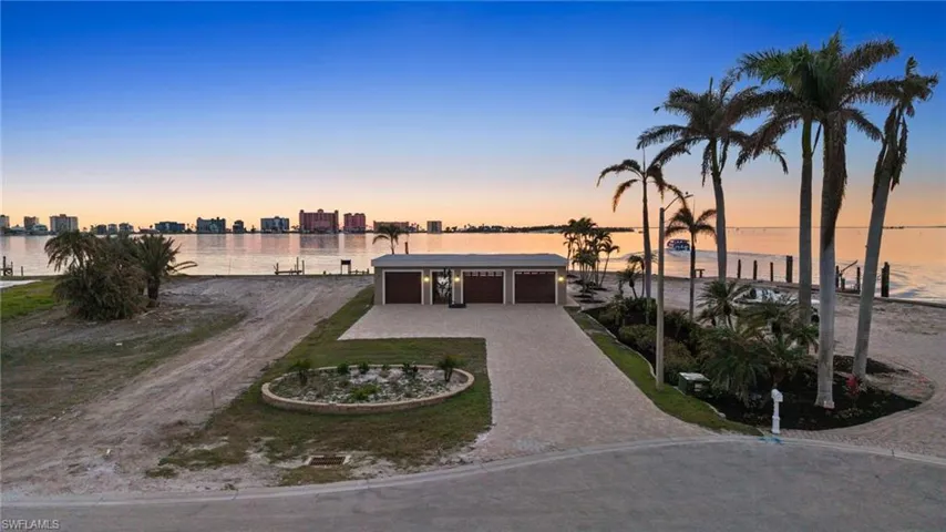 View of front of home with a water view, an outdoor structure, and a garage