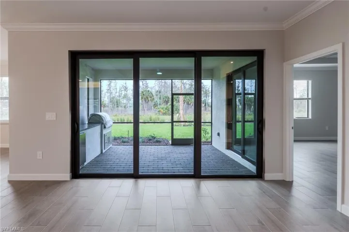 Interior hallway with panel doors leading to a room featuring large windows with blinds and a ceiling fan, and a bathroom with a tiled shower/tub combination and wood-finish flooring