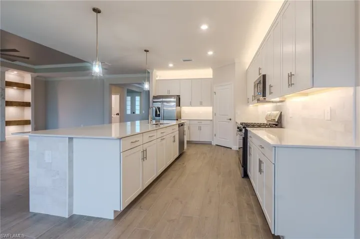Bathroom featuring a spacious walk-in shower with clear glass enclosure and tiled walls, a lengthy vanity with light-toned cabinetry and dual sinks, a large wall-mounted mirror, and wood-finish flooring
