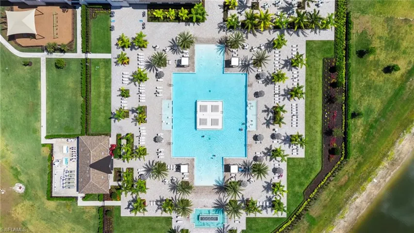 Resort-style aquatic amenity featuring a large swimming pool, surrounding paver patio, and multiple chaise lounges