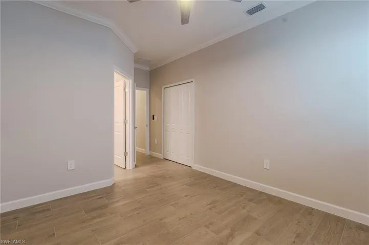 Spacious open-concept interior featuring wood-finish flooring, a contemporary ceiling fan, and a kitchen island with pendant lighting