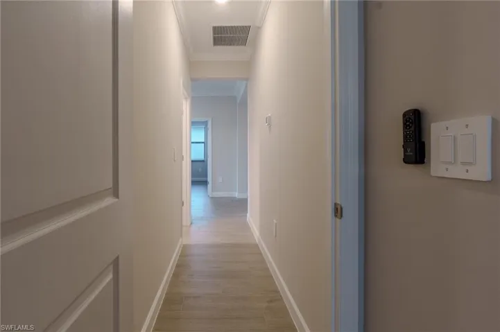 Hallway featuring wood-finish flooring, recessed lighting, and crown molding