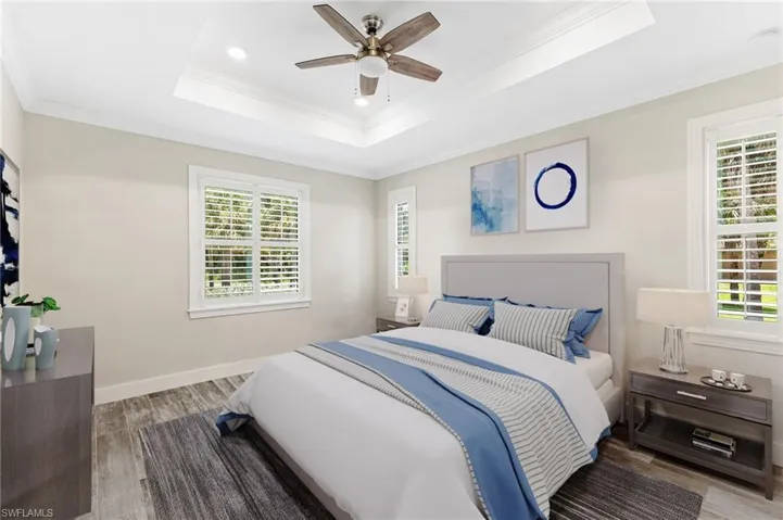 Owners Suite with a tray ceiling, ceiling fan, and double walk in closets