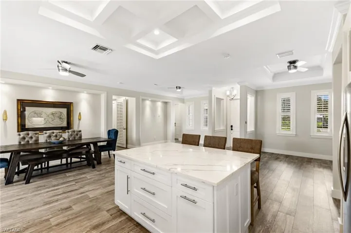 Kitchen with ceiling fan, a breakfast bar area, light hardwood / wood-style flooring, and white cabinetry