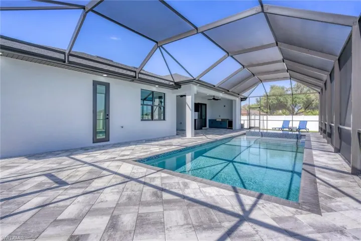 View of swimming pool with a patio, a ceiling fan, and glass enclosure