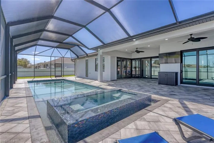 View of swimming pool with a ceiling fan, a patio, a pool with connected hot tub, and a lanai
