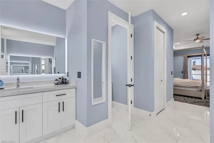Ensuite bathroom with baseboards, ceiling fan, recessed lighting, vanity, and marble finish flooring