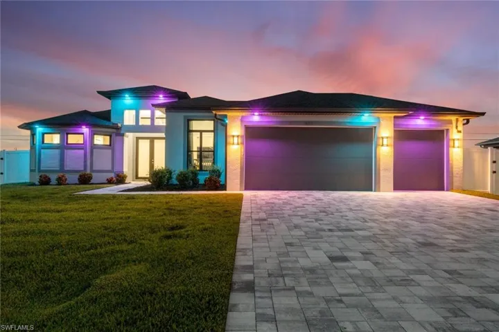 View of front of house with an attached garage, decorative driveway, a front yard, and stucco siding