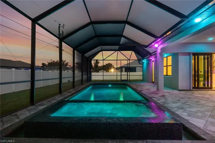 View of pool featuring a patio area, glass enclosure, and a pool with connected hot tub