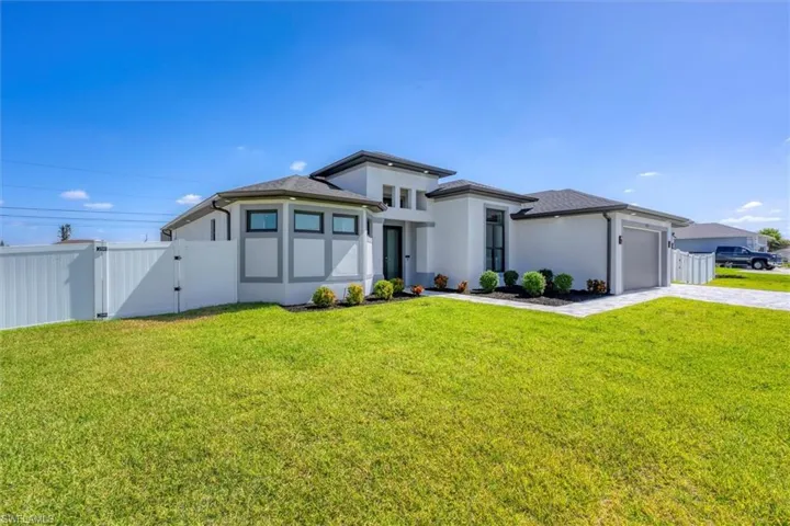 Prairie-style home featuring driveway, a gate, a garage, and stucco siding
