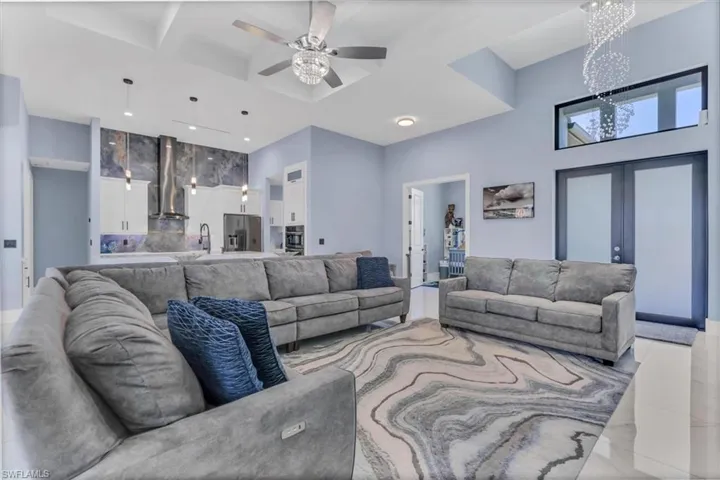 Living area featuring a chandelier, a towering ceiling, a ceiling fan, recessed lighting, and light marble finish floors