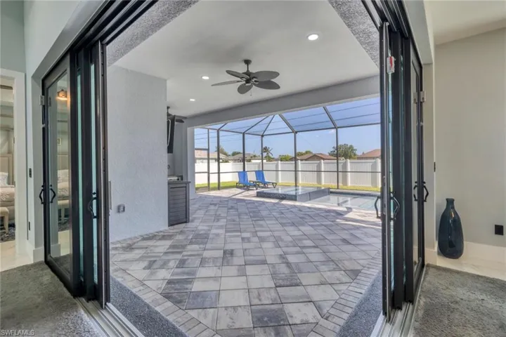 View of patio with ceiling fan, a residential view, and glass enclosure