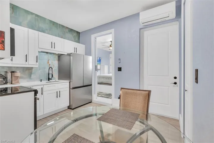 Kitchen featuring freestanding refrigerator, an AC wall unit, white cabinetry, and electric range