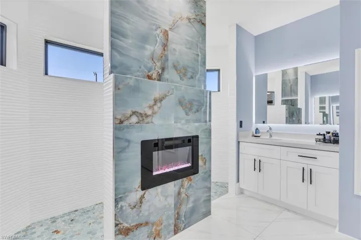 Full bathroom with marble finish flooring, a tile fireplace, walk in shower, and vanity