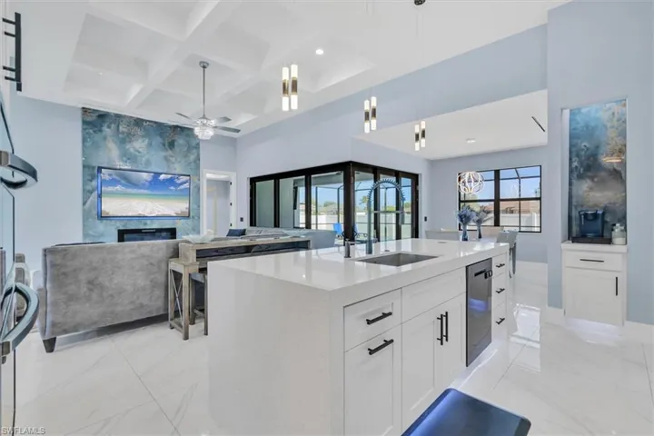 Kitchen featuring a sink, open floor plan, light marble finish floors, stainless steel dishwasher, and ceiling fan