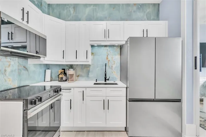 Kitchen with stainless steel appliances, a sink, and white cabinetry