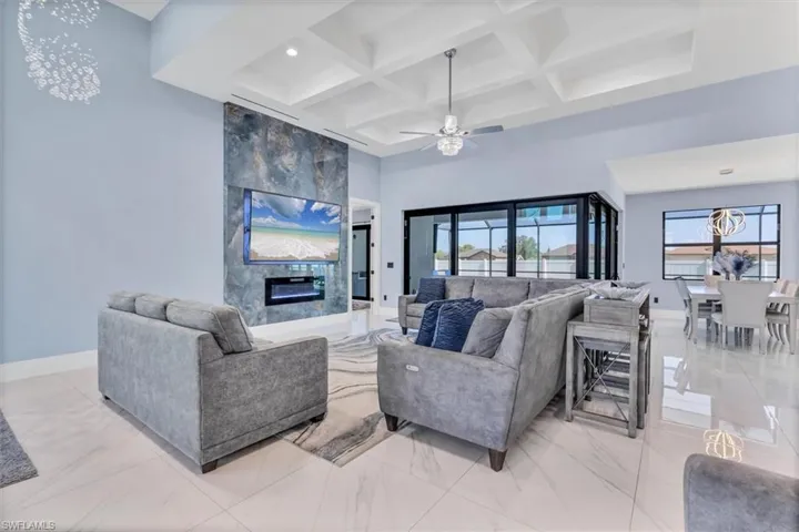 Living area featuring coffered ceiling, plenty of natural light, a premium fireplace, baseboards, and beam ceiling