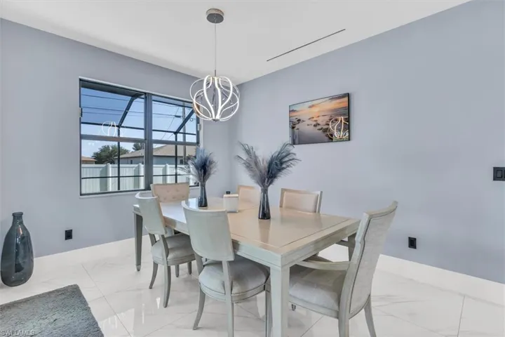 Dining room with light marble finish floors, baseboards, and a chandelier