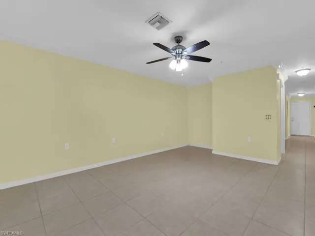 Spare room with ceiling fan, crown molding, and light tile patterned floors