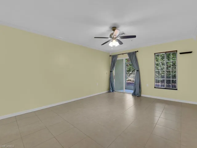 Empty room featuring a ceiling fan, crown molding, and tile patterned floors