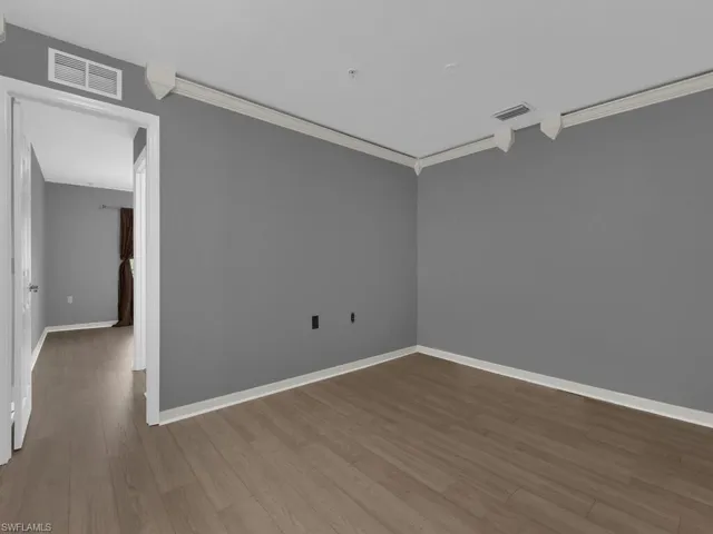 Unfurnished room with crown molding and wood finished floors