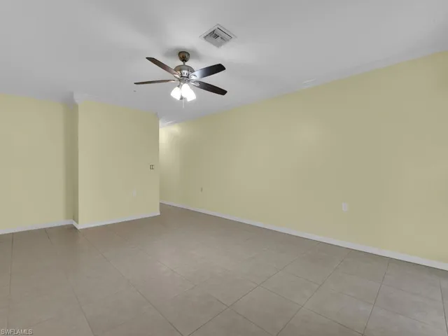 Empty room featuring ceiling fan, ornamental molding, and light tile patterned floors