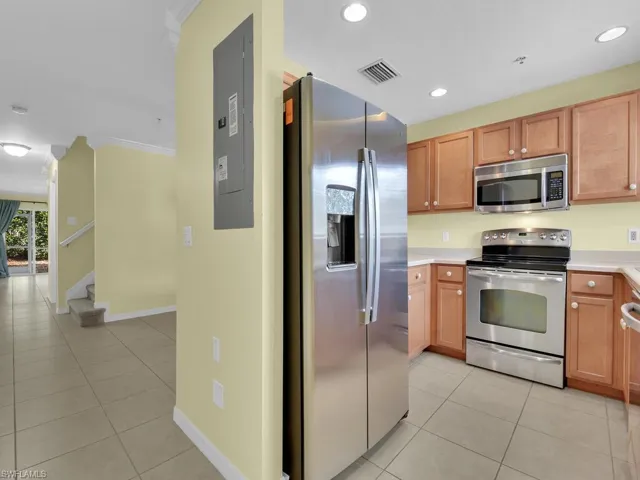 Kitchen with stainless steel appliances, light countertops, light tile patterned floors, electric panel, and ornamental molding