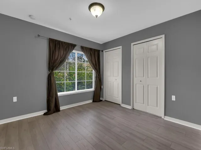 Unfurnished bedroom with two closets and wood finished floors