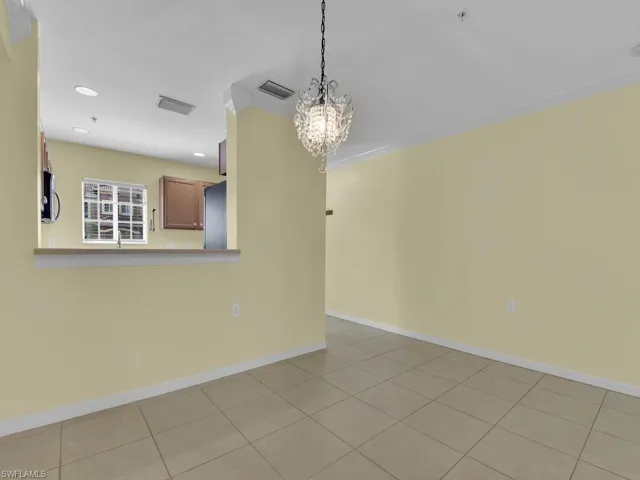 Unfurnished dining area with a chandelier, crown molding, and light tile patterned floors