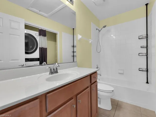 Full bathroom with vanity,  shower combination, light tile patterned floors, and stacked washer / drying machine