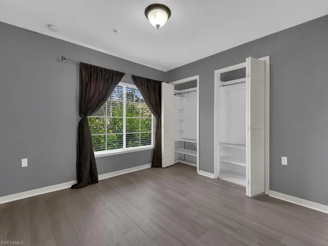 Unfurnished bedroom with two closets and wood finished floors