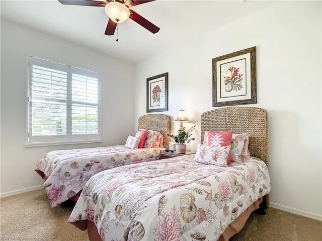 Large guest bedroom with plantation shutters and decorative ceiling fan