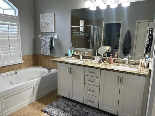 Ensuite with two sinks, granite countertop, tub, separate shower stall and plantation shutters