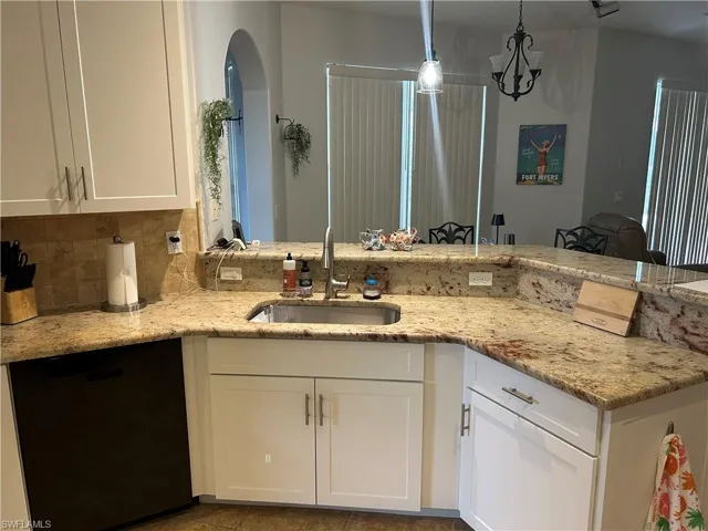 Kitchen featuring  tasteful backsplash, white cabinets, recessed lighting, and light stone counters