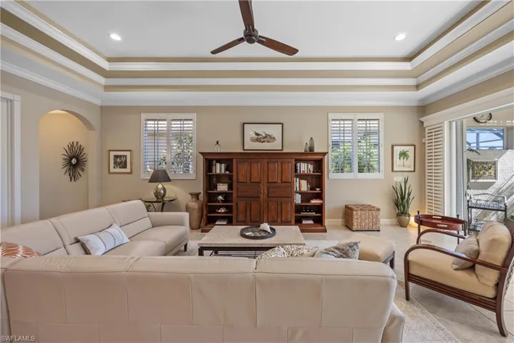 Carpeted living room featuring a healthy amount of sunlight, a raised ceiling, and ornamental molding