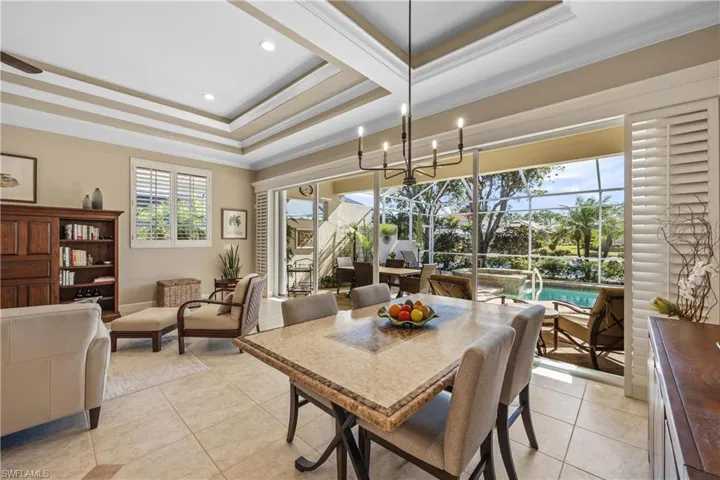 Dining room with a chandelier, light tile patterned floors, a tray ceiling, and crown molding
