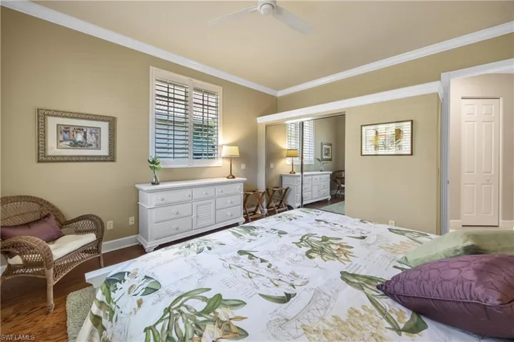 Bedroom with dark hardwood / wood-style floors, ceiling fan, and ornamental molding
