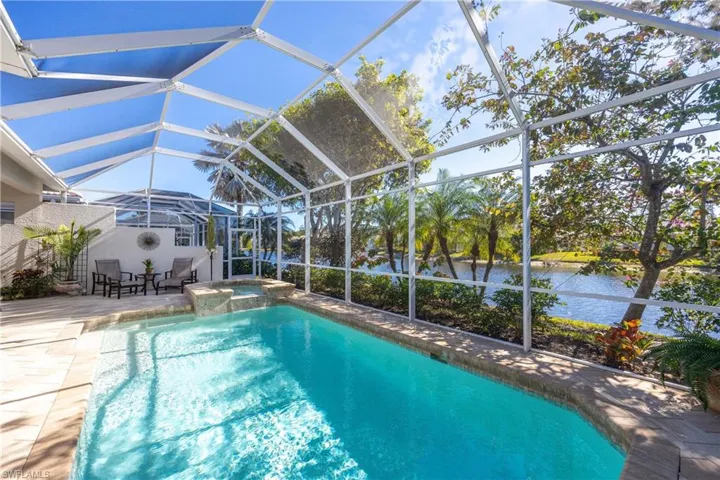 View of swimming pool featuring an in ground hot tub, a patio, a water view, and a lanai