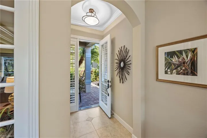 Tiled entrance foyer with french doors, a wealth of natural light, and crown molding