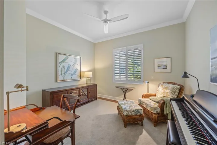 Carpeted office with ceiling fan and crown molding