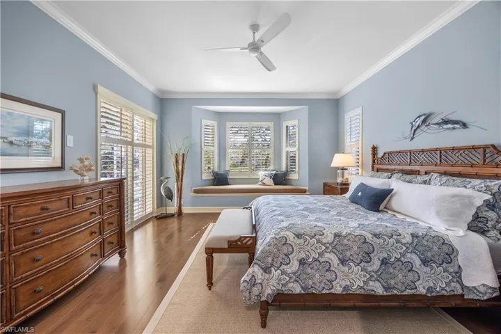 Bedroom with ceiling fan, crown molding, and dark hardwood / wood-style floors