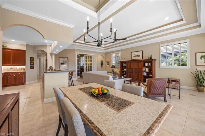 Dining room featuring a tray ceiling, ornamental molding, and a notable chandelier