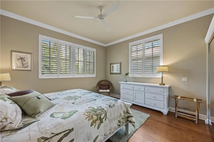Bedroom featuring multiple windows, ceiling fan, dark hardwood / wood-style flooring, and ornamental molding