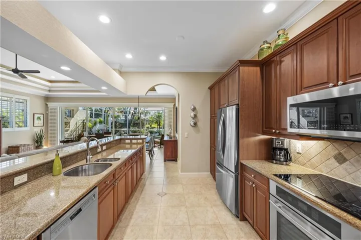 Kitchen featuring plenty of natural light, light stone countertops, sink, and appliances with stainless steel finishes
