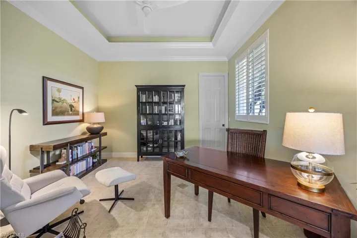 Tiled home office featuring a raised ceiling, ceiling fan, and ornamental molding