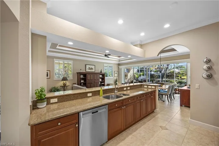Kitchen featuring stainless steel dishwasher, a healthy amount of sunlight, light stone countertops, and sink