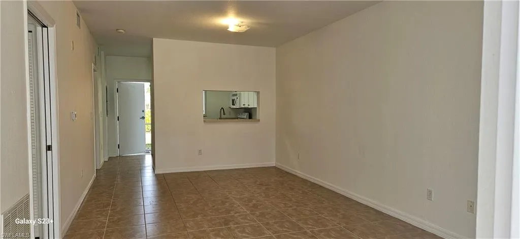 Spare room with baseboards and dark tile patterned floors