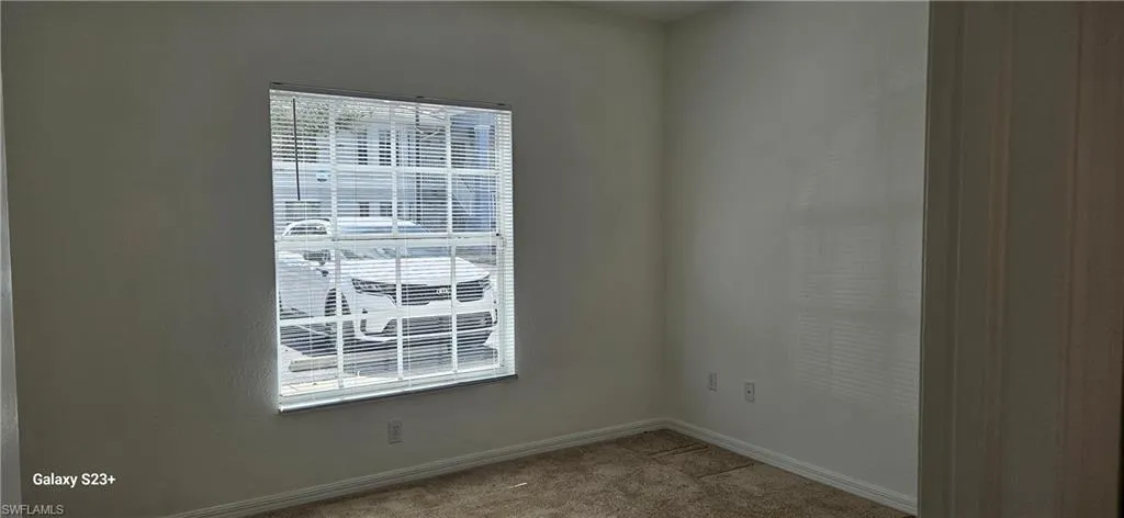 Carpeted spare room featuring baseboards