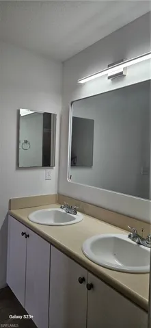 Bathroom featuring double vanity and a textured ceiling